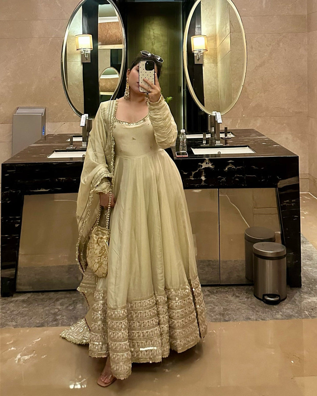 Person taking a mirror selfie wearing a traditional outfit in a bathroom.